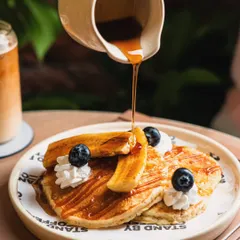 A thick stream of maple syrup being poured over a stack of pancakes. This classic action shot evokes a sense of indulgence and deliciousness.