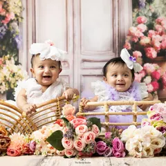 Double the smiles! This adorable studio portrait features twin baby girls sitting in wicker baskets surrounded by a beautiful floral setup. We love creating unique and charming scenes for sitter sessions.