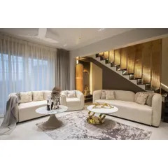 This living room in our Duplex Project features plush, comfortable seating and a stunning metallic accent wall along the staircase, blending texture and light for a luxurious feel.