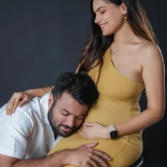 A tender moment where the father-to-be connects with his unborn child. The clean, dark background of the studio ensures that nothing distracts from this simple, emotional interaction.