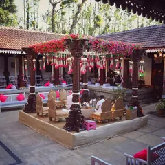 A wider view of the Thottimane courtyard wedding. The central mandap is the star, surrounded by low seating with bright pink cushions, allowing guests to be fully immersed in the traditional ceremony.