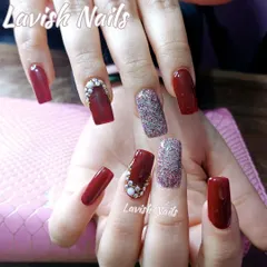 A rich, dark red manicure on square nails, featuring accent nails with full-coverage holographic glitter and delicate pearl and rhinestone clusters.