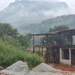 The mood at the site on a rainy day, with the hills disappearing into the clouds. The process of building is often a dance with the elements, a patient waiting for concrete to arrive while the landscape puts on a show.