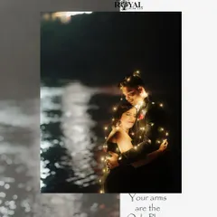 An intimate night portrait of a couple wrapped in fairy lights by the water, creating a dreamy and magical effect.