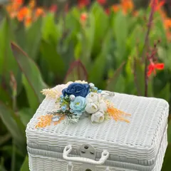 The same rattan suitcase, this time in white and decorated with a beautiful blue floral arrangement. This shows how a simple base can be customized for any theme or color scheme.