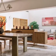 We designed this open-plan space in the Cocoon House to connect the dining and living areas, creating a natural flow. The transition from veined marble to rustic terracotta flooring defines the zones, while the consistent use of light wood furniture and neutral tones ensures a cohesive, airy feel.