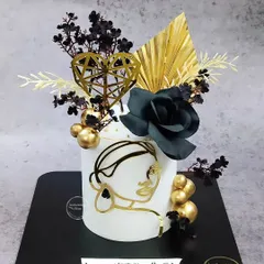 A striking black and gold floral cake for a woman of substance. This design uses a minimalist face outline, black roses, and gold accents to create a piece of modern art.