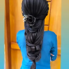 Showcasing advanced sculptural hair art, this style features a rose and a bow crafted entirely from hair. This unique and intricate braid is for the bride who wants a truly one of a kind look.