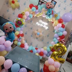 A colorful Cocomelon theme for a second birthday, perfect for a home party. The decoration includes a circular balloon arch in pastel colors, Cocomelon character foil balloons, and a light-up number '2'.