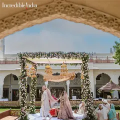 A beautiful view of an Anand Karaj ceremony at The Raj Palace, framed by a historic archway, as seen on Incredible India.