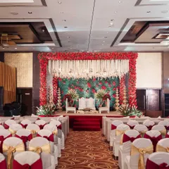This Sabyasachi-inspired mandap features a lush wall of greenery and red roses, framed by traditional floral pillars and hanging tuberoses, creating a look of timeless royal elegance.