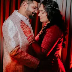 An intimate portrait of a couple during their engagement shoot. The warm, red lighting creates a romantic and passionate atmosphere.