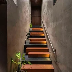 The interplay of raw materials can create powerful designs. We are inspired by staircases that use a simple palette, like the combination of concrete walls, terracotta-colored steps, and subtle step lighting seen here, to create a path that is both moody and beautiful.