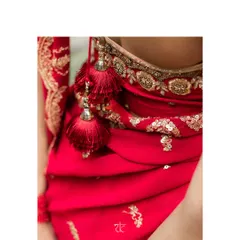A detail of the bridal ensemble, highlighting the delicate tassels and the intricate embroidery along the blouse and dupatta border, showcasing the fine craftsmanship involved.