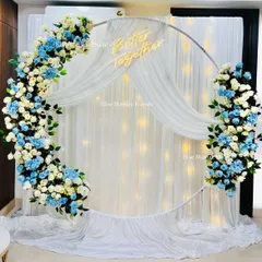 A beautiful engagement setup featuring a full ring backdrop adorned with white and blue flowers. The 'Better Together' neon sign adds a personal and romantic touch.