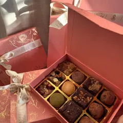 This is my Truffle Edition box, which includes my handmade dark chocolate truffles alongside the brownies and blondies. The sunlight here really shows off the beautiful pink and gold foil packaging.