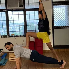 In this partner pose, I demonstrate a plank, providing a stable base for the student's warrior pose. This variation builds immense core strength for the base and balance for the flyer.