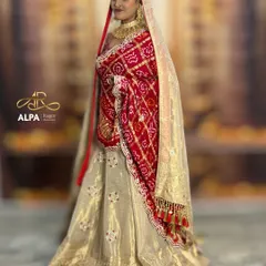A side profile highlighting the elegant bun and the way the bandhani dupatta is draped over the head. The makeup maintains its perfection from every angle.