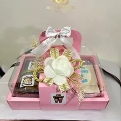 A beautifully packaged Rakhi hamper for your brother. This pink box includes a bento cake, tiramisu, cookies, and a rakhi, all elegantly decorated with a white floral arrangement.