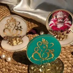 I can customize these resin stands with different idols and colors. This image shows a few variations, including a teal Ganesha, a white Ganesha, and one featuring a photo of a spiritual figure.