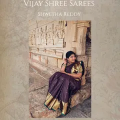 Shwetha Reddy, one of our cherished 'Queens', looks regal in a deep purple Kanjivaram silk saree with a classic gold border, pictured against a backdrop of heritage architecture.
