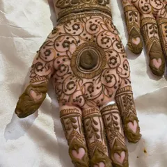 A close-up of a traditional mandala design on the palm, with cute heart details on the fingers.