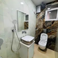 This bathroom features a wall-mounted toilet and a compact vanity to maximize floor space. The dramatic, dark-veined tile on the back wall serves as a stunning accent feature.