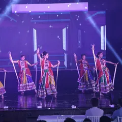 This stage performance showcases a dandiya routine with intricate patterns and formations, enhanced by professional stage lighting.