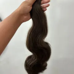 Here I am holding a thick weft of wavy tape-in extensions, showing the rich color and healthy sheen of the hair. This is a great option for adding both volume and a soft wave.
