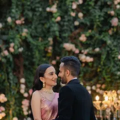 An intimate portrait of the couple against a wall of flowers, with soft lighting creating a romantic and dreamy atmosphere.