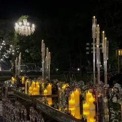 A glamorous reception dinner setup featuring mirrored tables that reflect the warm glow of countless candles and the sparkle of overhead chandeliers. This design is all about luxury and drama.