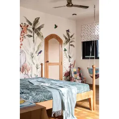 For this kids' room, I chose a boho-chic theme with a lively tropical jungle wallpaper. An arch-shaped door finished with veneer and rattan leads to a hidden walk-in wardrobe, adding a touch of playful mystery.