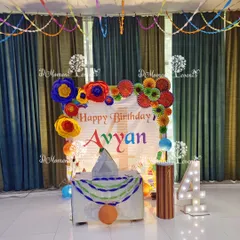 A creative and colorful Art & Craft themed birthday for a 4-year-old. Instead of balloons, the backdrop is decorated with handmade paper flowers and pinwheels, with a light-up number "4" and a craft-themed cake table.