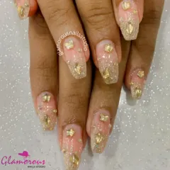 Dripping in gold. This extravagant design features a sheer glittery base adorned with gold stars, gems, and other 3D charms for a look that is pure opulence.