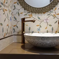 A close-up of a beautifully detailed wash area. The design features a floral mosaic tile backsplash, a patterned ceramic vessel sink, and a bronze-finish tap for a touch of traditional elegance.