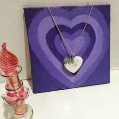 This heart-shaped resin pendant has a milky white base with flecks of green, creating a beautiful and subtle piece of jewelry.