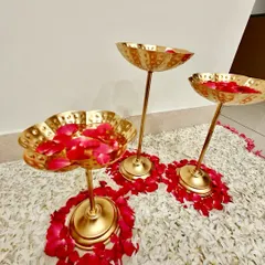 Elegant decor for a housewarming ceremony, with brass floral stands holding red rose petals on a carpet of white petals.
