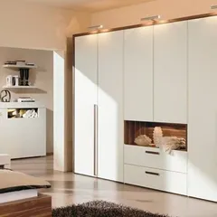 A sophisticated bedroom wardrobe in white and wood tones, featuring an open niche for display and integrated overhead lighting.