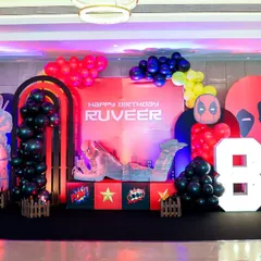 An epic stage setup for a Deadpool-themed 8th birthday, featuring a massive character cutout, marquee numbers, and dramatic lighting.