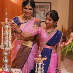 There's nothing more special than creating matching outfits for a mother and daughter. Seeing them share a moment like this, lighting a lamp together in coordinated pink and blue traditional wear, is the reason I pour my heart into every piece.