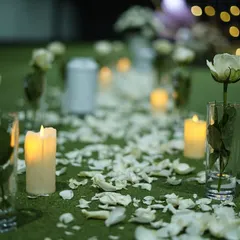 The pathway to "I do". We created this romantic aisle for a proposal using scattered white rose petals and single white roses in glass vases, with the soft glow of candles lighting the way.