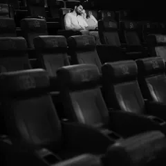 A quiet, intimate moment captured in black and white. The couple sits together in the empty theatre, creating a feeling of having a world all to themselves.