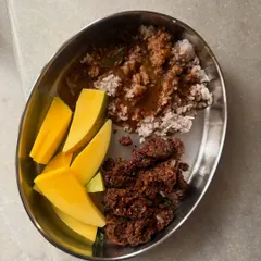 A comforting plate of horsegram palya saaru with rice and fresh raw mango, a perfect example of a balanced and soulful meal.