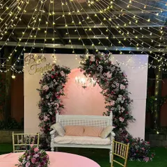 A romantic 'Better Together' setup perfect for an anniversary or engagement party. The fairy light canopy, pink floral arch, and elegant white bench create a perfect photo opportunity.
