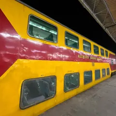 The distinctive red and yellow exterior of the double-decker express train at a station platform at night.