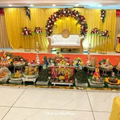 This photo shows an extensive Seer Thattu arrangement in front of the main stage. The display includes traditional dolls, peacock figures, and decorated coconuts, adding to the festive grandeur.
