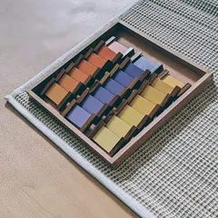 The color tablets are a key sensorial material used to refine a child's chromatic sense. This set, known as Color Box 3, challenges the child to grade nine different shades of color, developing a keen eye for detail and an appreciation for beauty.