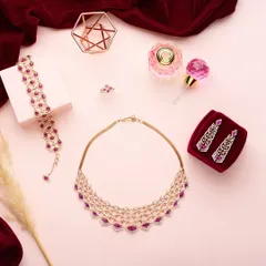 A rich, luxurious flat lay for PNGadgil and Sons. The deep red velvet and soft pink background create a romantic mood, perfectly complementing the ruby and diamond jewelry set.