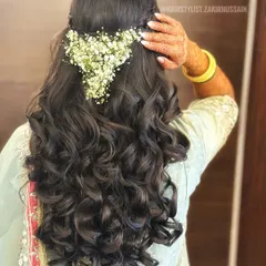 For this Mehendi look, I styled the hair in a half-updo with a braided crown and voluminous curls. I then created a heart shape using fresh baby's breath for a unique and romantic touch.
