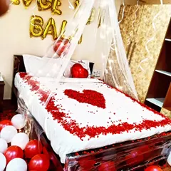 A classic romantic bedroom decoration. I used red and white balloons, a heart made of rose petals on the bed, and a delicate canopy to create a special atmosphere.